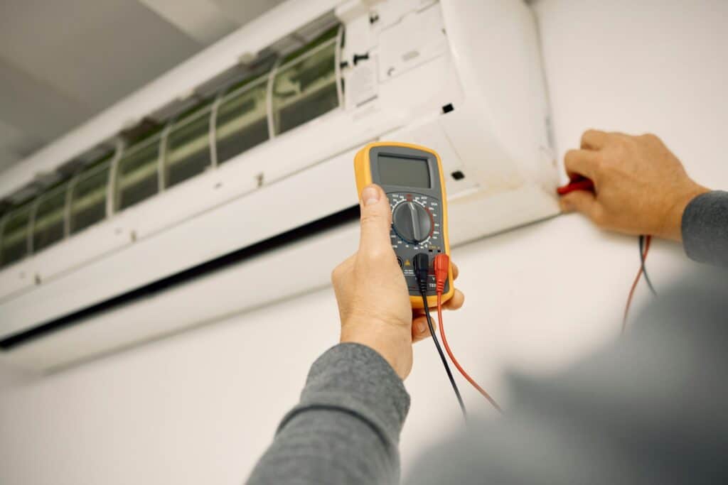 Air conditioner, maintenance hands and voltage meter with construction, wall and technician man. AC