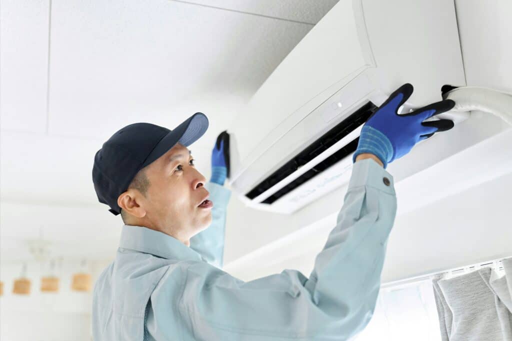 Asian worker inspecting air conditioner