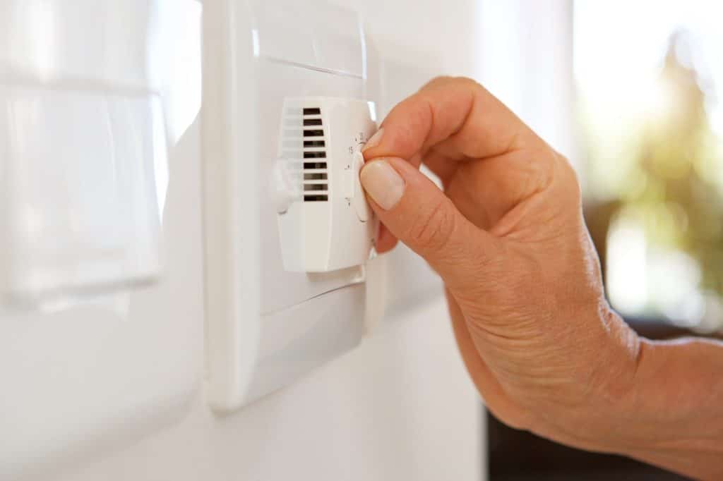 female hand adjusting temperature with dial on air conditioning