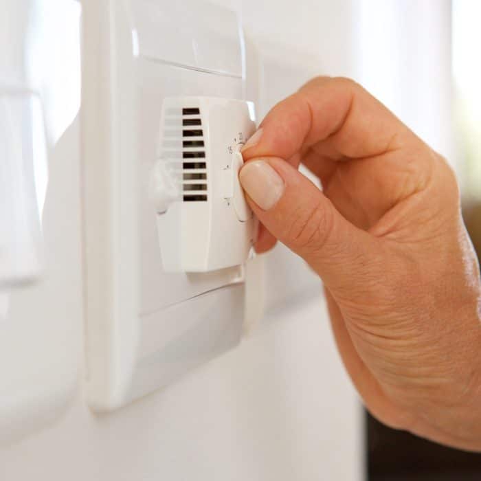 female hand adjusting temperature with dial on air conditioning